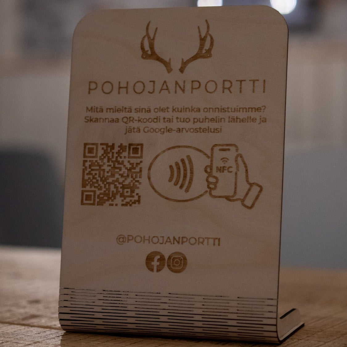 Koivuvanerinen arvostelukyltti ravintolan pöydällä – skannaa QR tai kosketa puhelimella (NFC) ja jätä Google-arvostelu